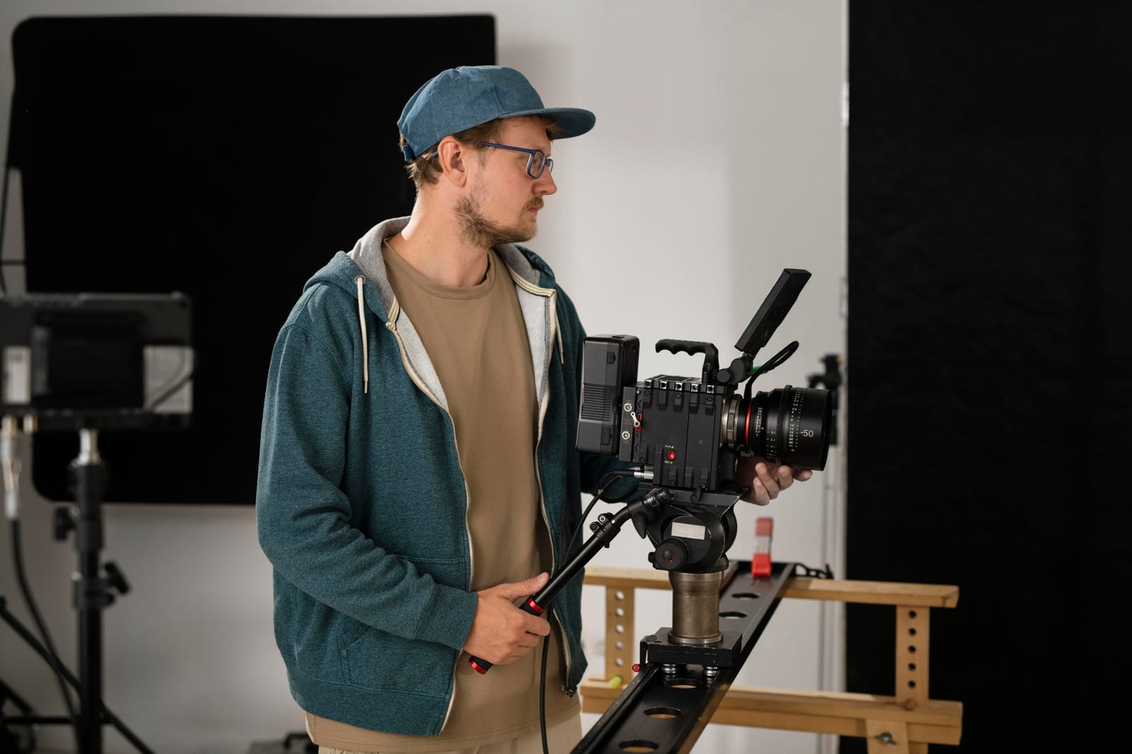 Operador de boné posiciona uma câmera de cinema sobre slider em um estúdio
